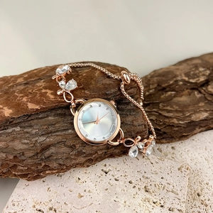 Detail of rose gold bracelet watch with rhinestone accents on rustic stone display