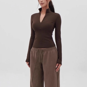 Detail of slim-fit dark brown yoga top with half-zip collar and matching joggers