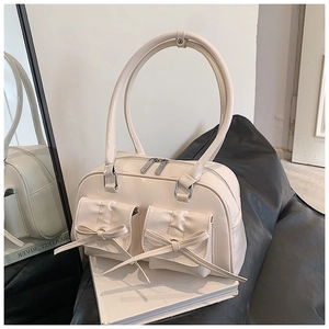 Close-up of cream PU leather shoulder bag with bow pockets and round metal handle