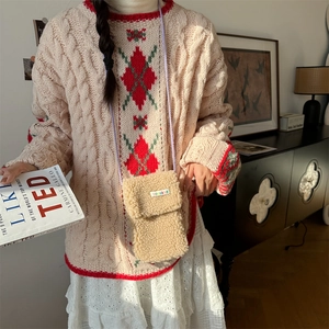 Detail of beige plush crossbody phone bag with purple strap on knit sweater outfit