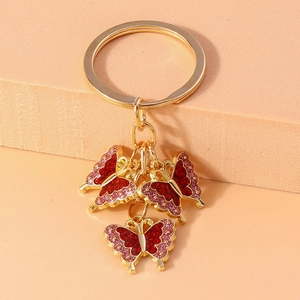 Detailed macro view of golden keychain featuring three red and pink glitter butterflies