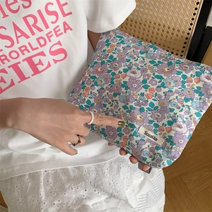 Floral cotton makeup pouch with colorful botanical pattern held by a model in a natural setting