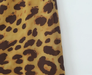 Vue macro du tissu en mousseline à motif léopard avec taches marron et noir sur beige