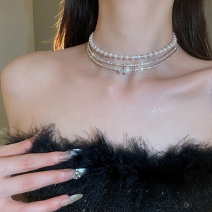 Close-up of layered pearl choker with shimmering rhinestone chains on model neck