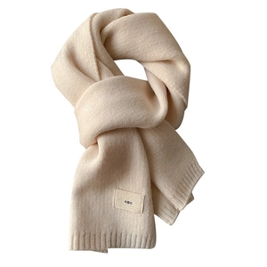 Soft cream knit scarf with minimalist emo woven tag against a clean white background