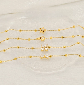 Detail of four gold stainless steel bracelets with zircon star and floral motifs