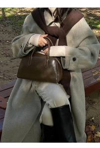 Close-up of a dark brown leather handbag styled with a winter coat and warm scarf