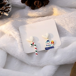 Close-up of asymmetrical Christmas earrings featuring a candy cane and a cute snowman