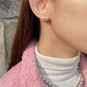 Detail view of pink gold glass pearl stud earrings worn with elegant outfit