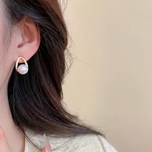 Elegant gold drop earring featuring a single large pearl shown on a model