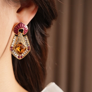 Close-up of vintage gold earring with brown gem and enamel detail on a model