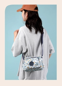 Detail showing the floral nylon crossbody bag with adjustable strap on a female model