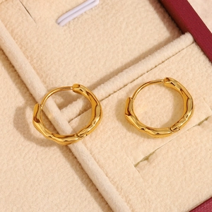 Close-up of golden irregular round earrings on premium beige velvet jewelry box