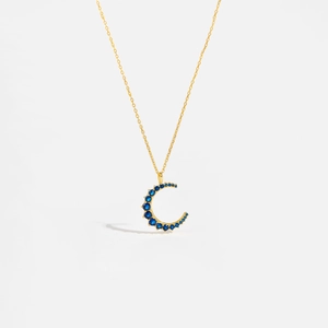 Detail of S925 silver moon pendant with blue crystals on a fine gold chain