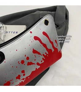 Detailed view of silver creative cleaver handbag with red splatter pattern on soft fabric