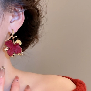 Close-up of vintage deep red flower earrings with golden hooks worn by a model