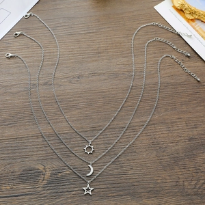 Vue détaillée des colliers avec pendentifs soleil lune et étoile sur fond en bois sombre