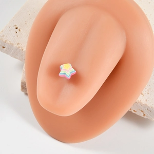 Detailed view of rainbow star tongue ring displayed on skin-toned silicone ear model