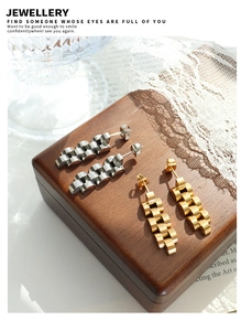 Details von gold- und silbernen Ohrringen im Gliederarmband-Stil auf Holz-Display