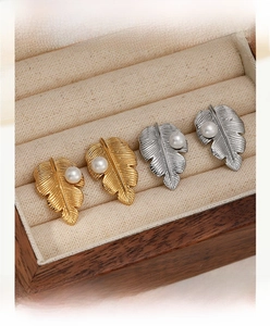 Détail de boucles d'oreilles perles en forme de feuille, finitions or et argent sur coffret