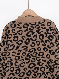 Detail shot of leopard print knit cardigan showing fine texture on a wooden hanger