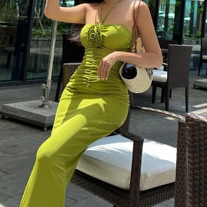 Detail of a bright green backless dress featuring a large 3D floral accent on the neck