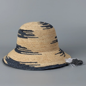 Dettaglio cappello di paglia rafia intrecciato a mano con strisce e cordino regolabile
