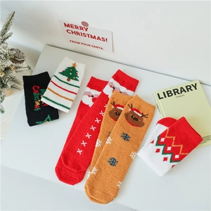 Détail de chaussettes de Noël en polaire corail avec motifs festifs de rennes et Père Noël