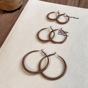 Brown hoop earrings set in three sizes on a book with a vintage aesthetic look