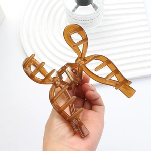 Elegant amber resin hollow bow hair claw clip with golden spring held in hand