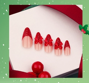 Detail of red French press-on nails with 3D bows and winter sweater texture
