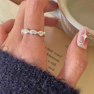Makroaufnahme eines S925 Silbermuschelrings am Finger mit elegantem Strickärmel-Detail
