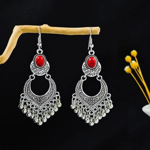 Vue macro de boucles d'oreilles bohèmes argentées avec pierre rouge et franges