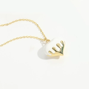 Detailed view of a white peach heart pendant with gold crown drip accent on a fine chain