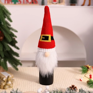 Detail of knitted Christmas gnome wine bottle cover with red pointed hat and faux fur