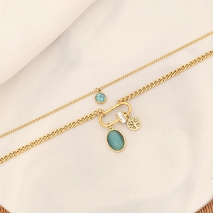 Detail of gold layered necklace with turquoise, green gem, and tree of life charms
