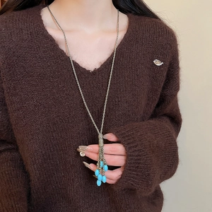 Detail of bohemian tassel necklace with blue teardrop beads on a brown sweater