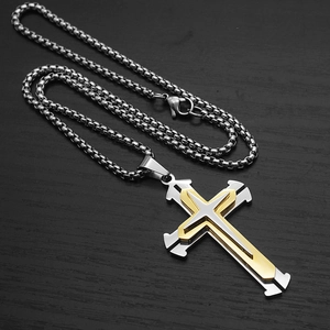 Close-up of a three-layer split cross pendant in silver and gold steel on a box chain