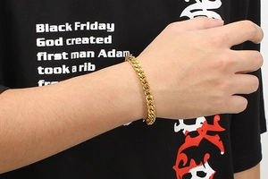 Close-up of a golden stainless steel Cuban link bracelet on a male model wrist