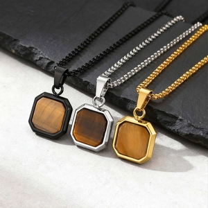 Close-up of square stainless steel necklaces in black, silver, and gold with tiger eye stones