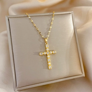 Detail of gold cross pendant with sparkling zircons on a beige leather display stand