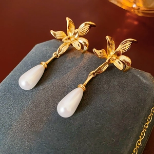 Detailed close-up of 14K gold plated flower stud earrings with elegant teardrop pearls