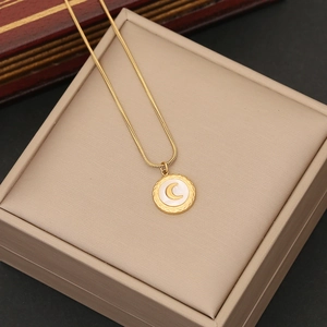 Close-up of gold snake chain necklace with round white pendant featuring a golden crescent moon