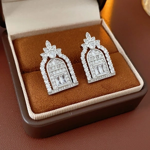 Detailed macro view of silver arch earrings with rectangular zircon in brown velvet box