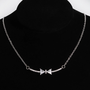 Detailed view of a silver bow pendant with zircon stones on a black neck mannequin