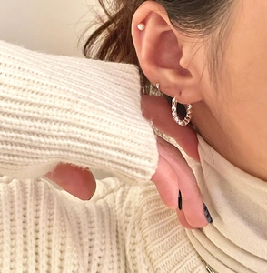Close-up of S925 sterling silver textured hoop earring and small white pearl stud on ear