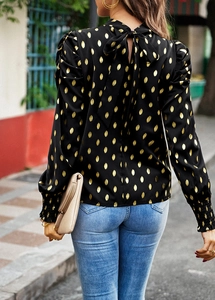 Detail of elegant black long-sleeve blouse with golden polka dots and bow tie on the back