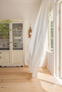Close-up of cream striped curtains with elegant ball tassel trim and vertical texture