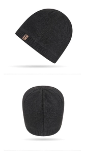 Detailed view of the black knit beanie with premium brown leather logo patch and seam texture