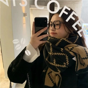 Detail of thick knitted plaid scarf in black and khaki geometric pattern for winter